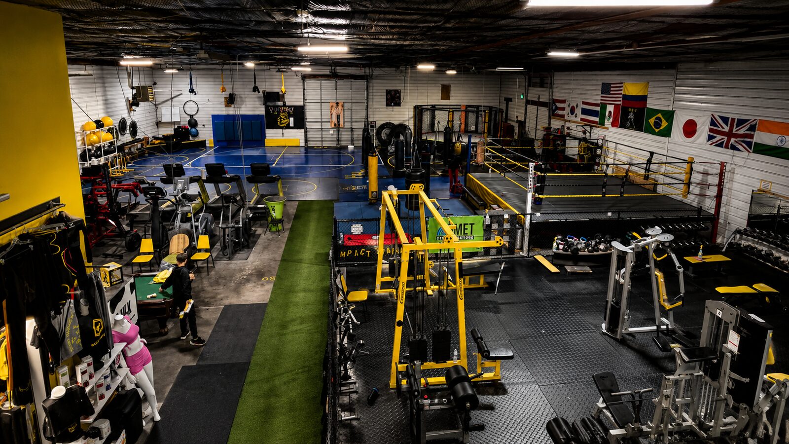 Interior of the Sud'n Impact gym in Fort Wayne showing the martial arts mat, boxing ring, MMA cage and strength training floor